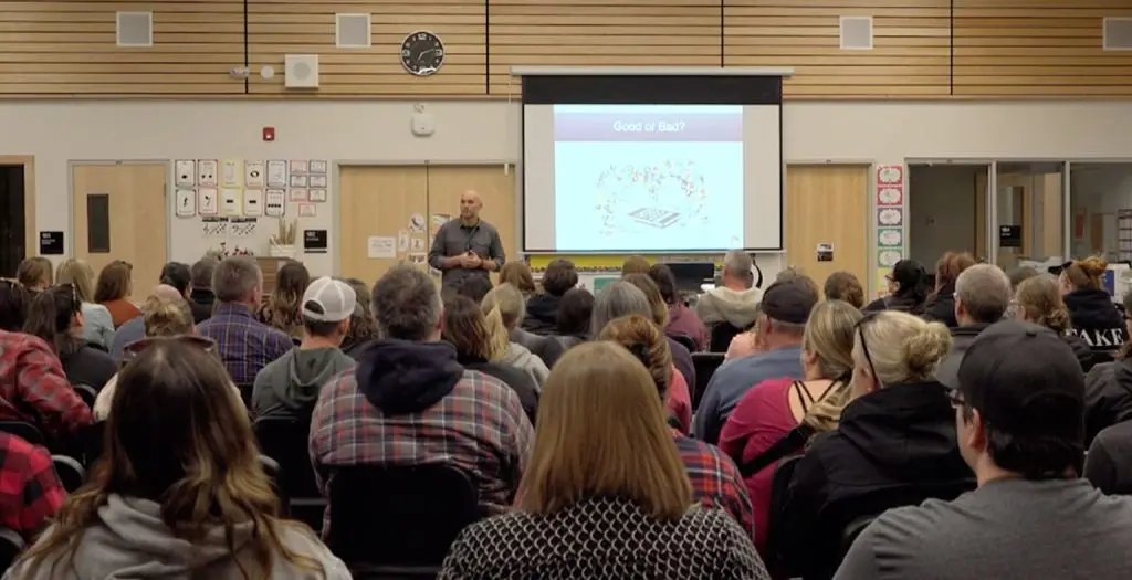 Speaker presenting online safety information to parents at a school seminar.